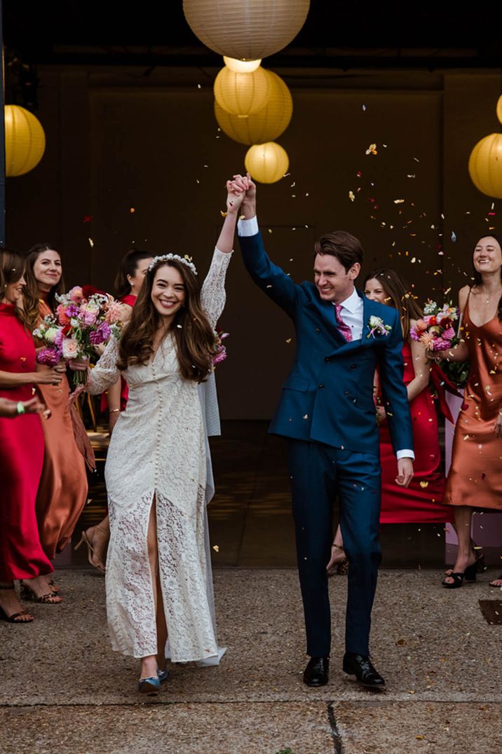 The bride in a lace wedding dress has a confetti exit with the groom in a blue suit for their city wedding in London