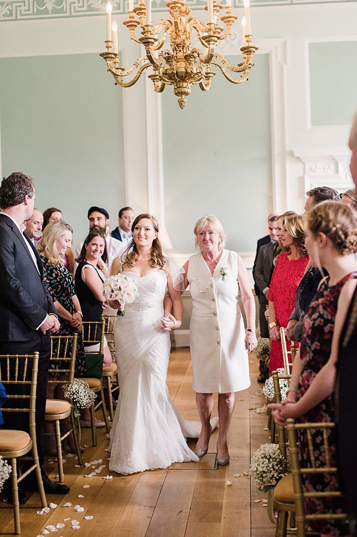 Bride in classic strapless wedding dress walking down the aisle with mother of the bride at Botleys Mansion London wedding venue 