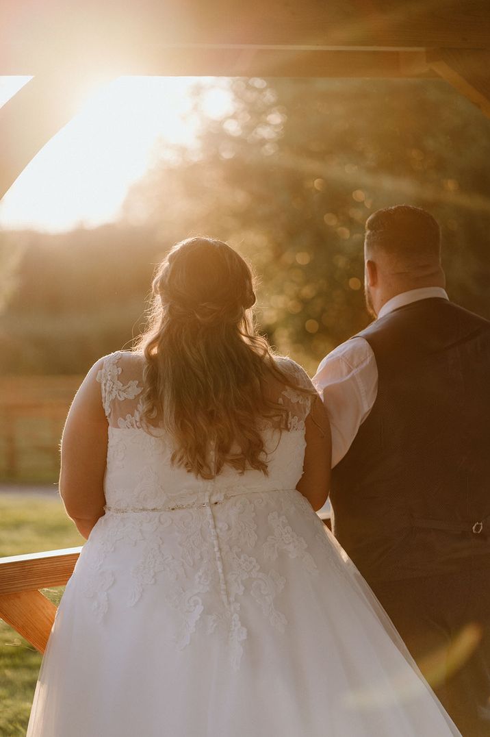 Golden hour wedding photography of the bride and groom looking out across the view at their wedding venue 