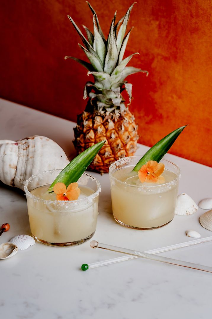 Pineapple and sage wedding cocktail with edible flower decoration and salted rim 