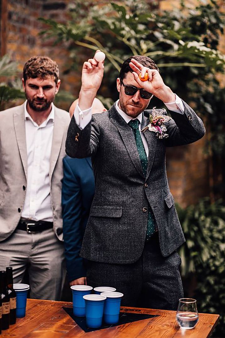 Groom and groomsmen play beer pong 