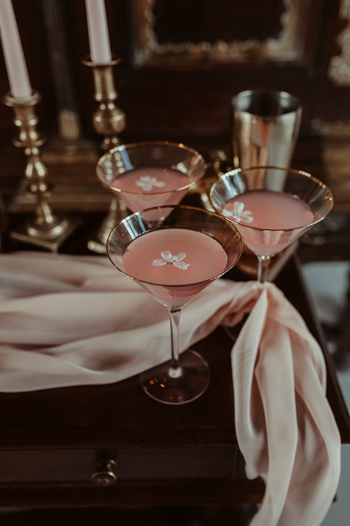 Cocktail glasses with pink cocktails with white edible flower decorations 