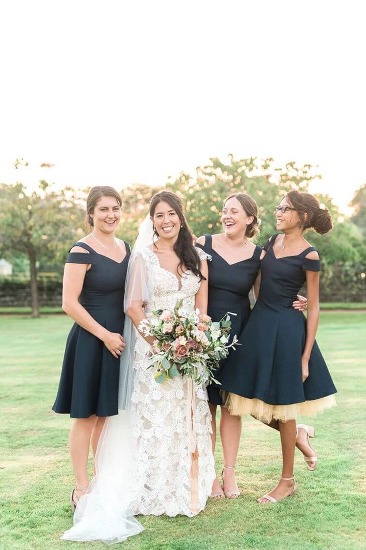 Three bridesmaids wearing short capped off-shoulder sleeve navy bridesmaid dresses, one had a ruffled tulle underskirt | Emma Pilkington Photography