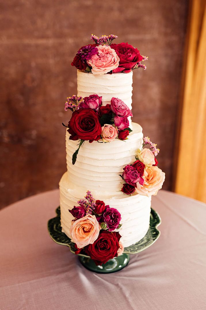 Three tier wedding cake with icing and rose decor at traditional wedding