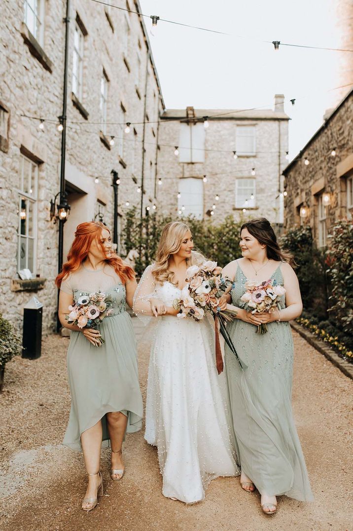 Bridesmaids in light green bridesmaid dresses with bride in pearl embellished wedding dress 