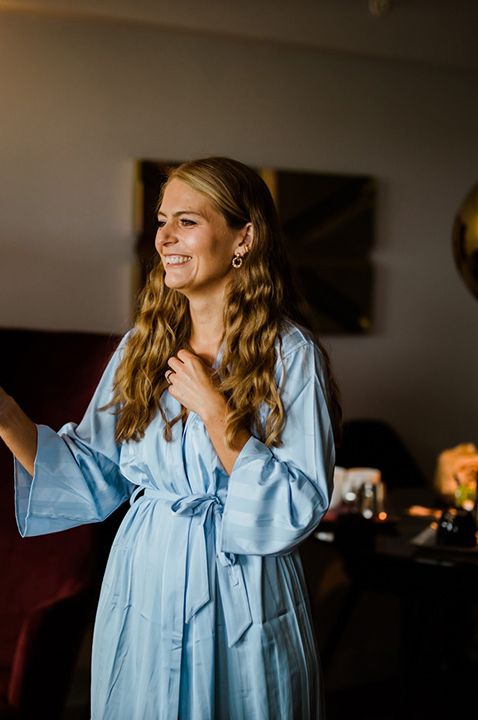 Maid of honour in baby blue robe with champagne glass