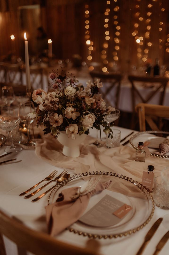 Romantic neutral blush pink cosy wedding Christmas wedding tablescape with warm twinkling candlelight 