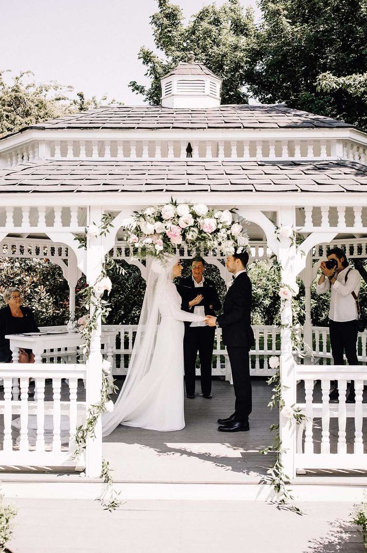 British Muslim bride holding hands with her groom at an outdoor wedding ceremony 