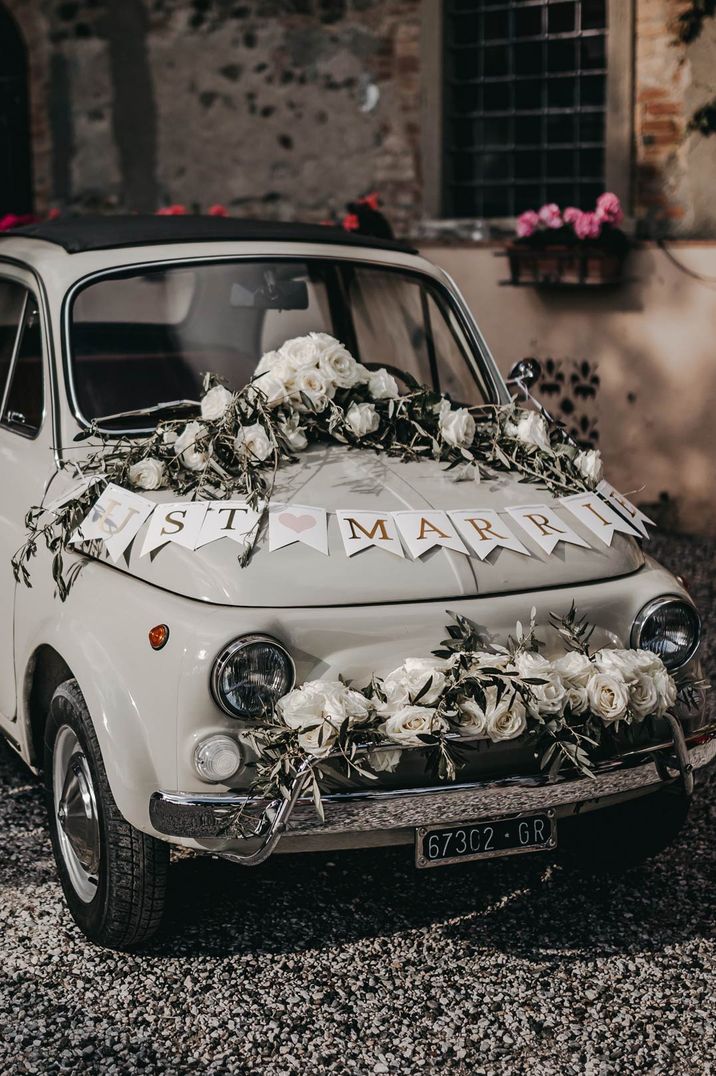 White Fiat 500 with "Just Married" banner and floral rose decorations to decorate a wedding car