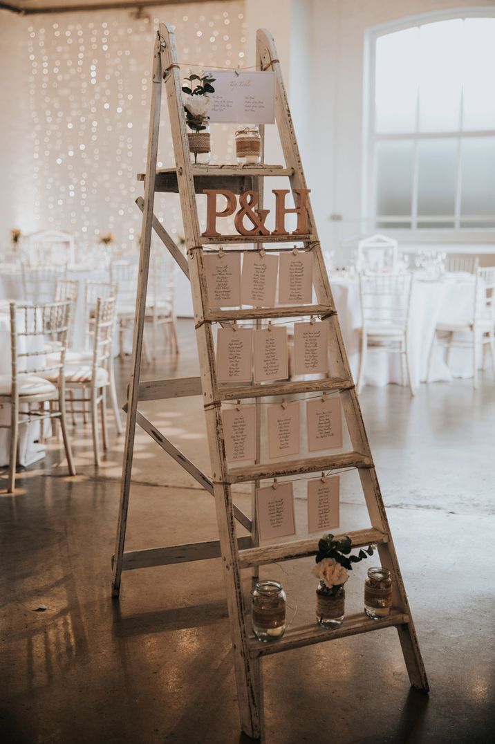 Rustic white painted ladder with initials, pegs and mason jars with flowers 