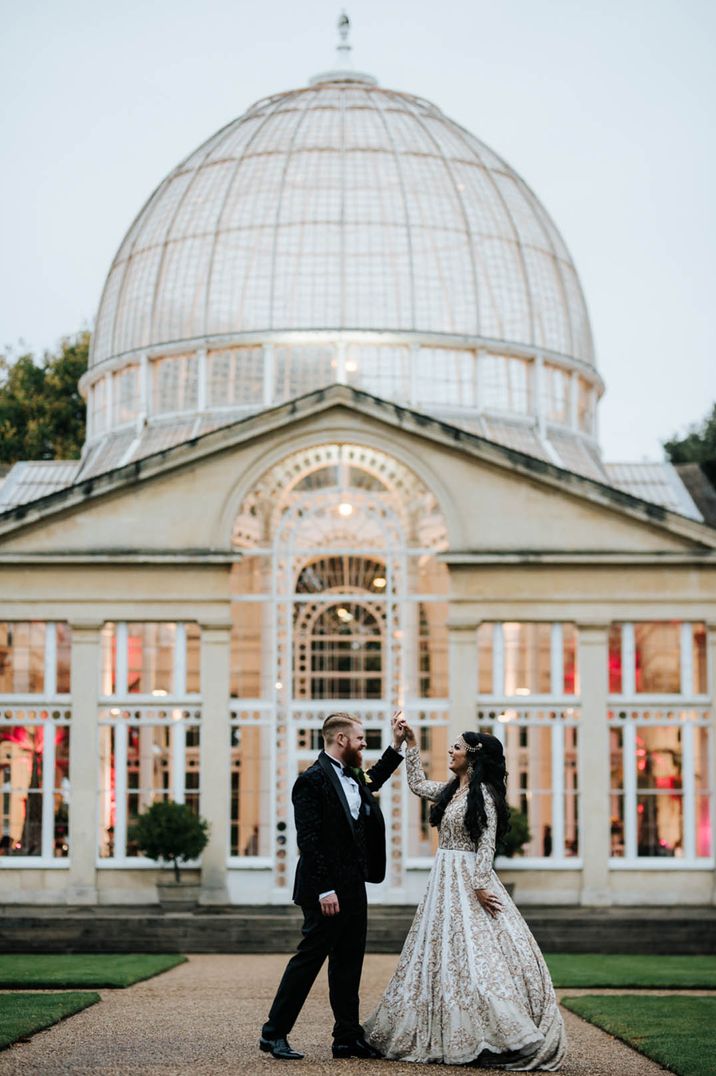 Syon Park wedding venue featured in Bridgerton with the groom in black tie and bride in ivory and gold embroidered outfit 