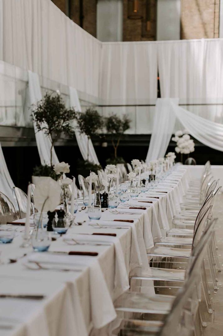 Minimalistic white wedding tablescapes with white wedding table cloths, white wedding drapes and white rose table centrepieces 