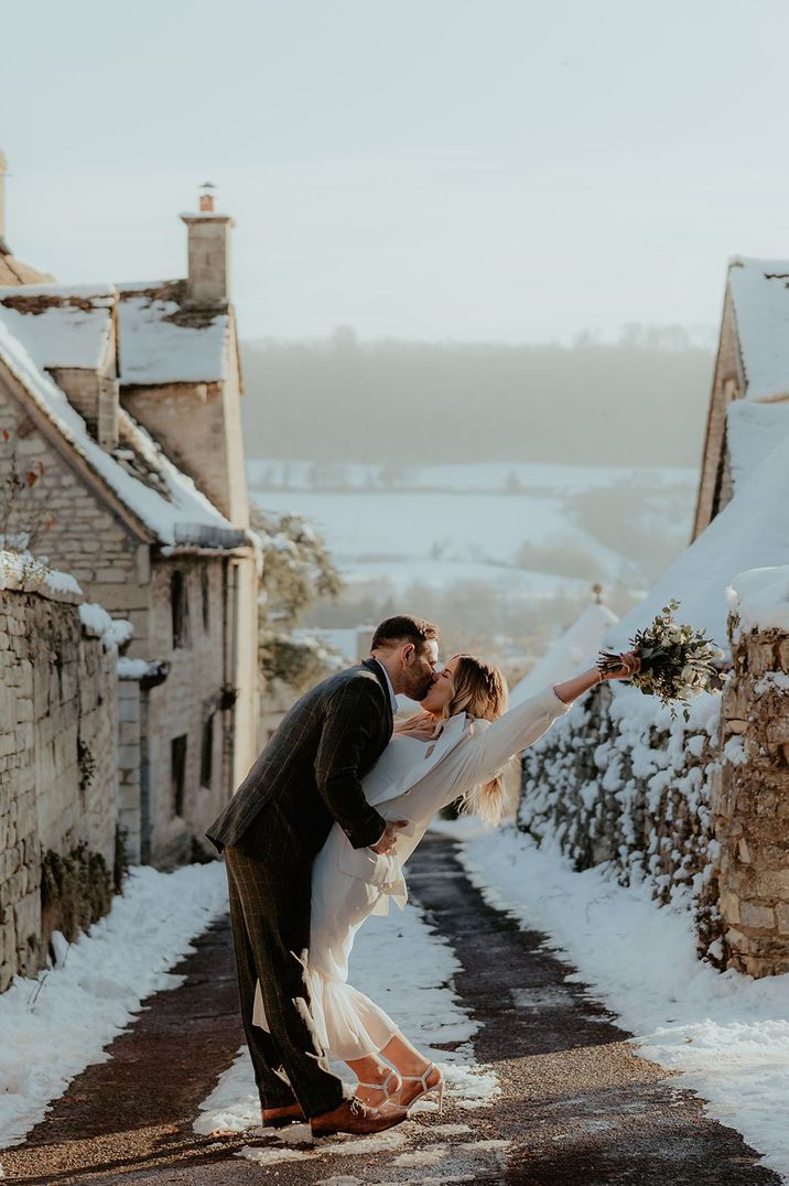 Groom kisses the bride on their snowy wedding day 