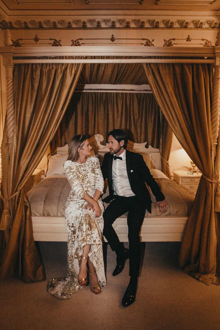 Bride in sequin Abigail Gardenia dress and groom in black tux on bed