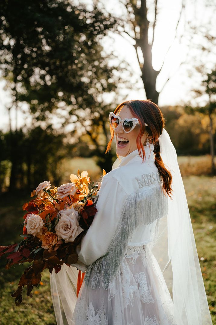 Bride wears heart shaped sunglasses and white denim personalised jacket 