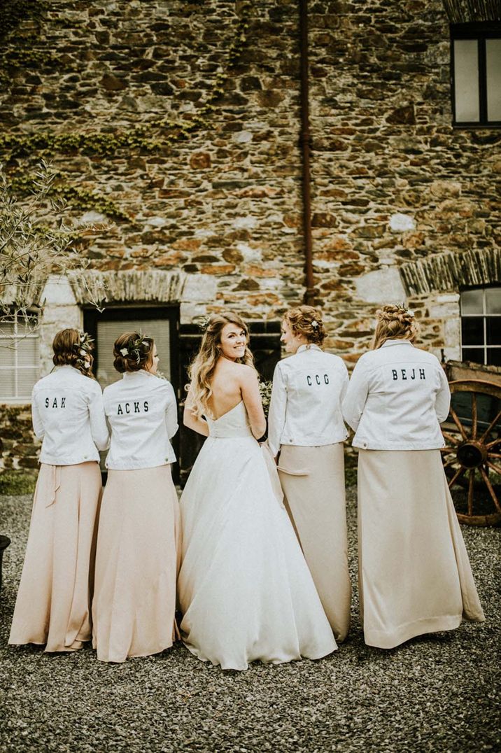 Bridesmaids in white denim jackets with their nicknames on the back with the bride for fun bridal party wedding photo 