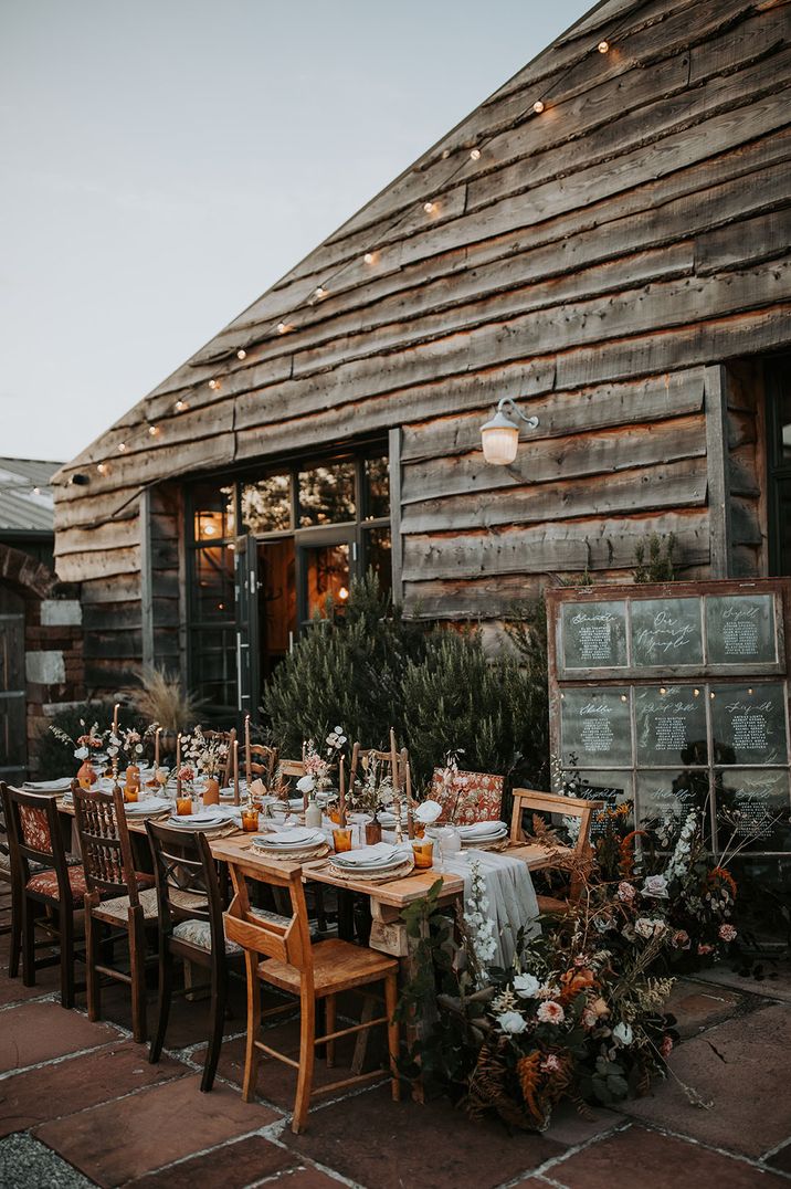 Outdoor wedding tablescape with window table plan sign and autumnal tablescape with brown taper candles 