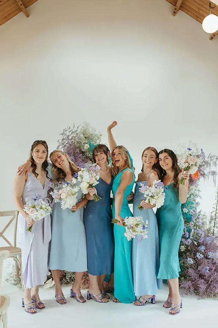 Bridesmaids wearing blue-toned mismatched spring bridesmaid dresses 