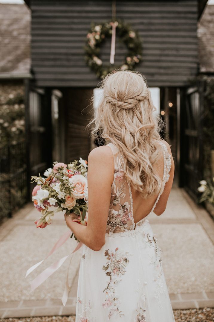 Bride in a floral embroidered wedding dress with a half up half down wedding hairstyle 