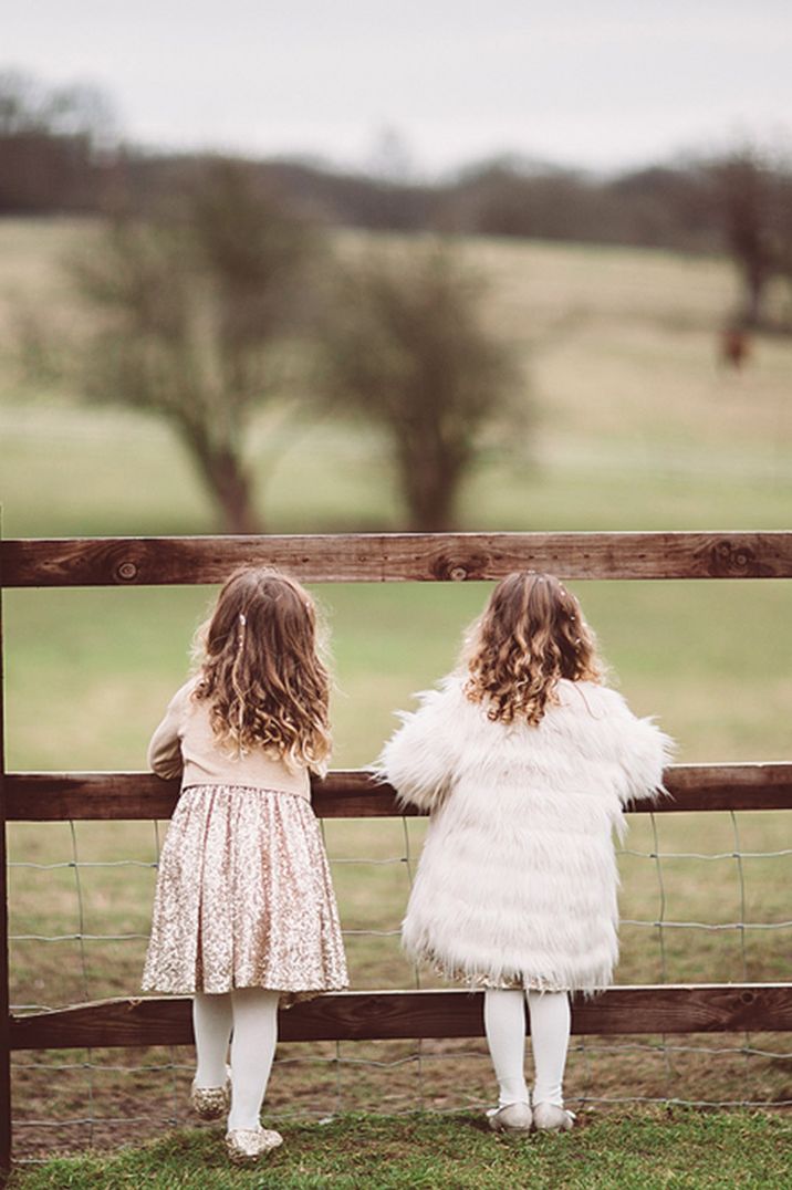 Flower girl in sequin dress and other flower girl in fluffy white coverup 