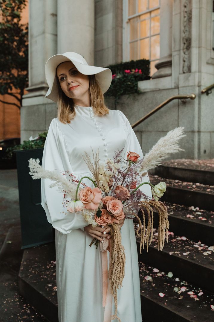 Bride wears floppy sun hat and vintage wedding dress