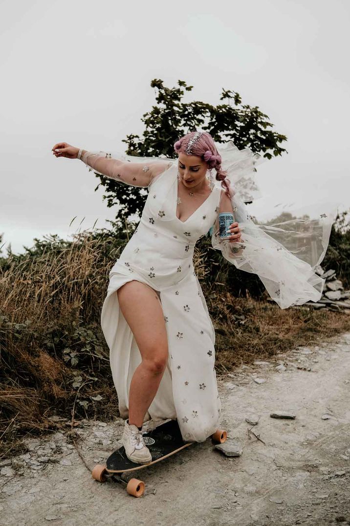 Bride in a tulle wedding dress with pattern and front slit riding a skate board