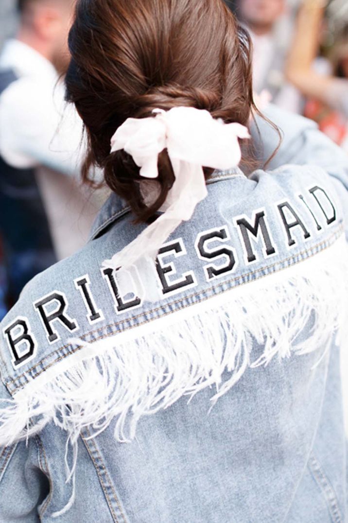 Bridesmaid in light blue denim cover-up with white tassels and black and white lettering 