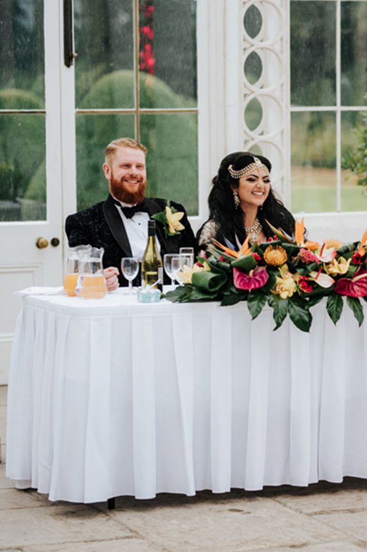 Bride and groom sit at their sweetheart table at Syon Park glasshouse wedding venue 