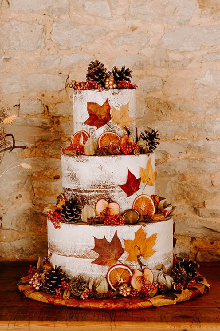 Autumn leaves decorate three tier semi-naked frosted wedding cake for autumn wedding 