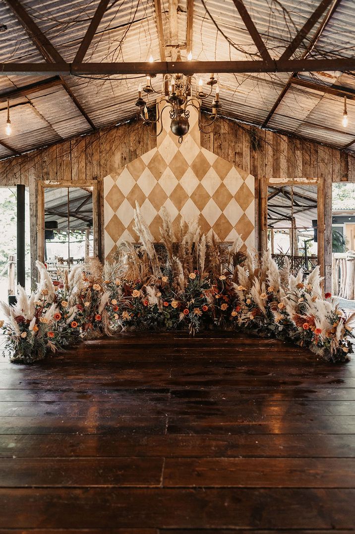 Dark orange and light peach roses with pampas grass altar decorations at barn wedding 