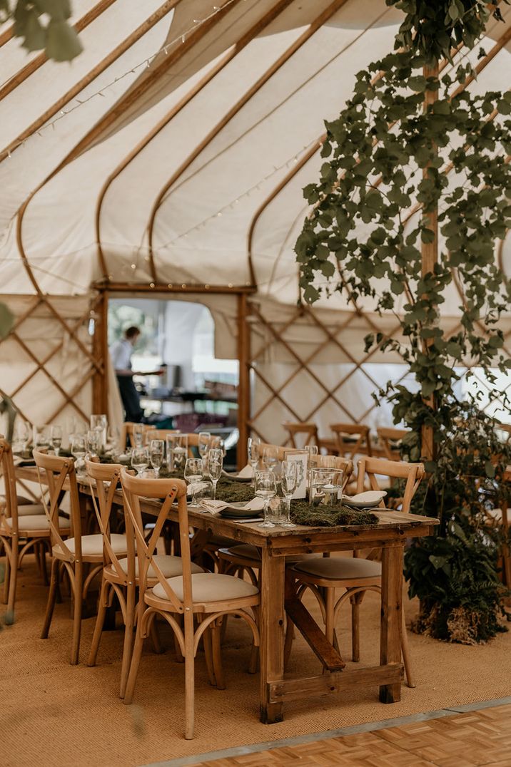 Camp Katur marquee wedding venue with long wooden banquet tables with moss and greenery decor 