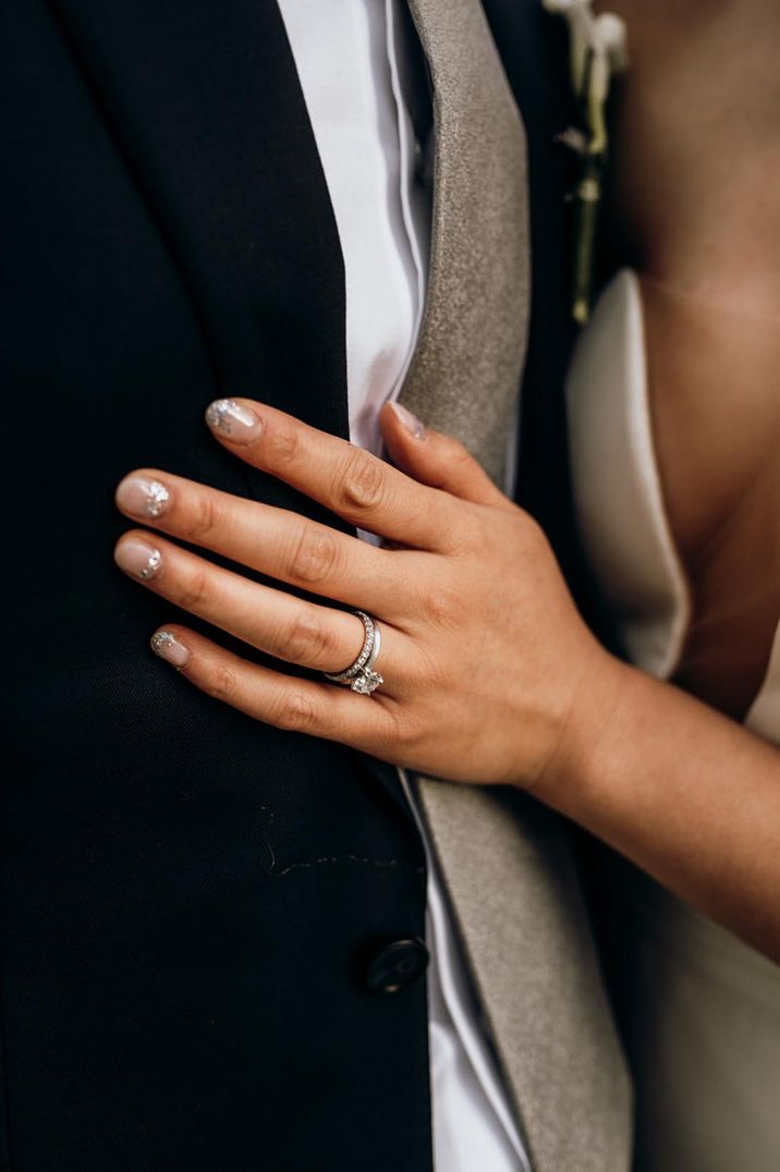 Bride with glittery nails wearing a diamond engagement and wedding band 