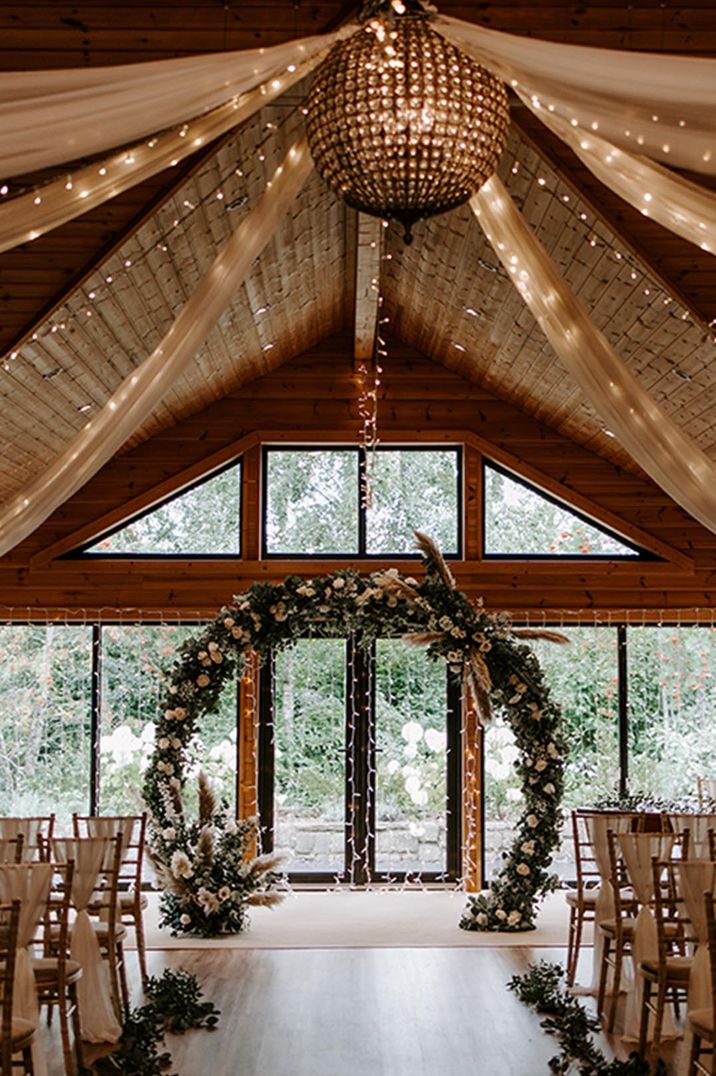 Rustic and cosy wedding venue with fairy lights and floral moongate altar decoration 