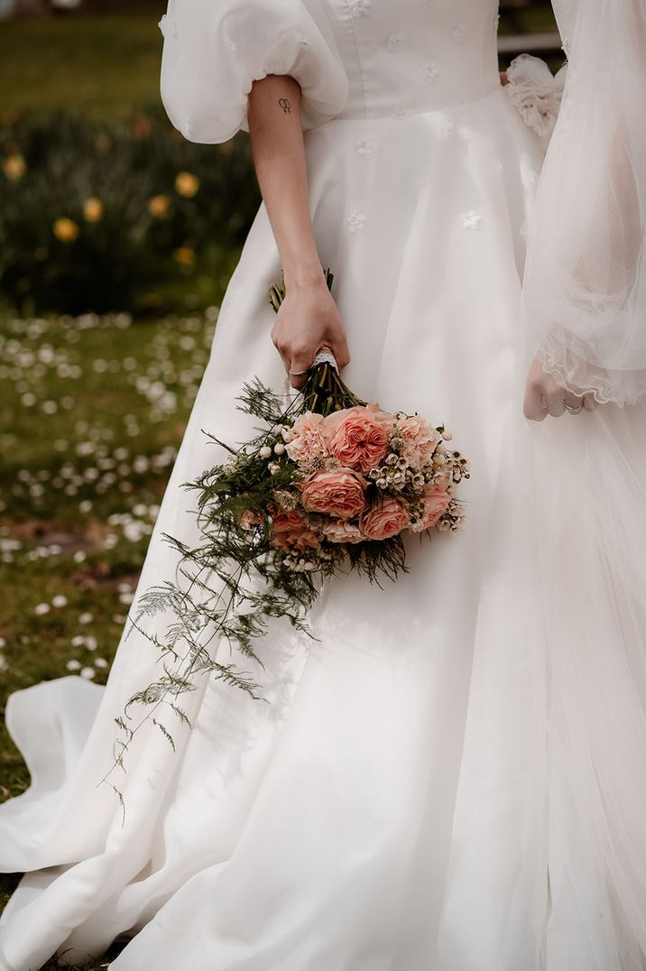 Bride carrying pink and white wedding bouquet with wax flowers and carnations 