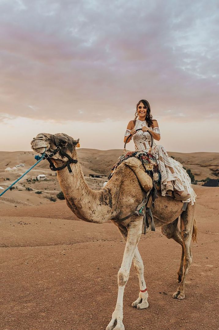 Bride in boho lace wedding dress riding on camel for desert wedding in Marrakech 