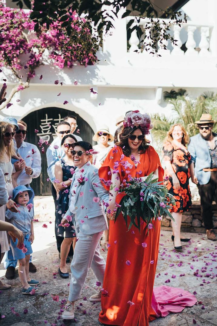 Couple walk through pink confetti on their wedding day after marrying