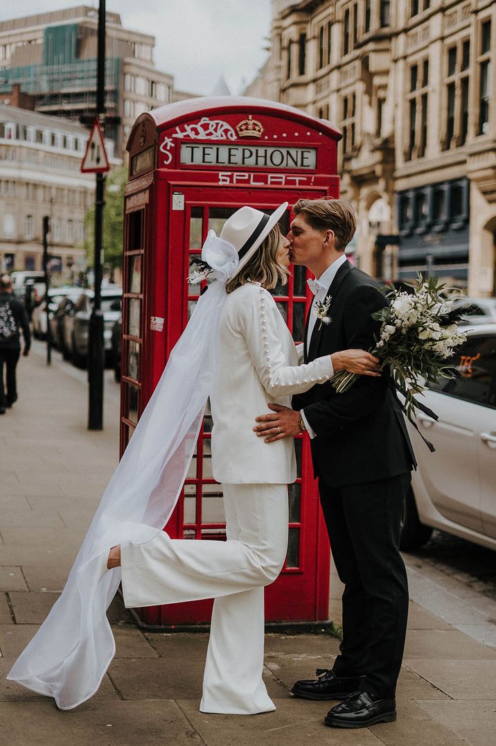 Bride and Groom have London wedding as they share a kiss in front of a red phone booth 