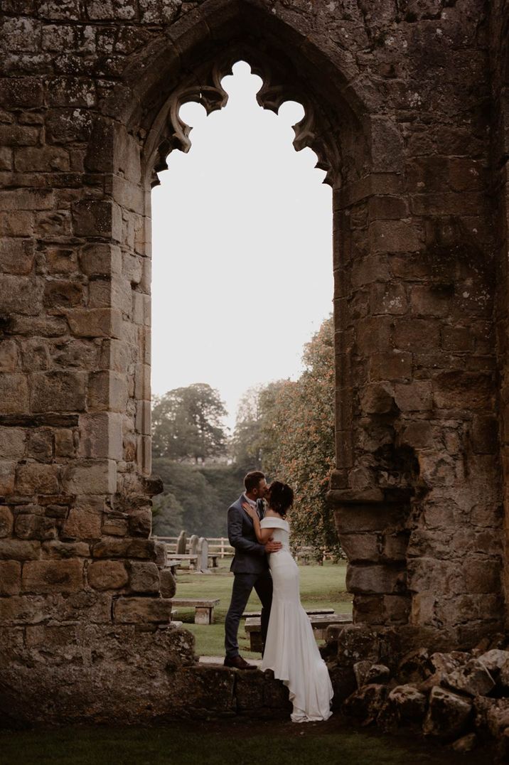 Bride and groom standing in large historic archway at Tithe Barn wedding venue