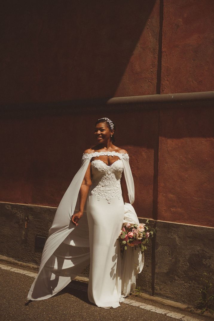 Bride wears sheer wedding cape with floral appliqué to the front 