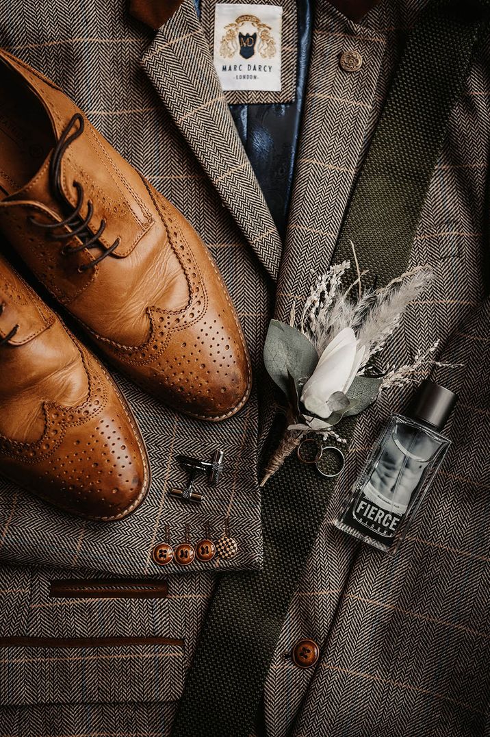 Brown leather brogue groom shoes on grey checkered suit jacket from Marc Darcy with white flower buttonhole and silver cufflinks with Abercrombie and Fitch cologne 