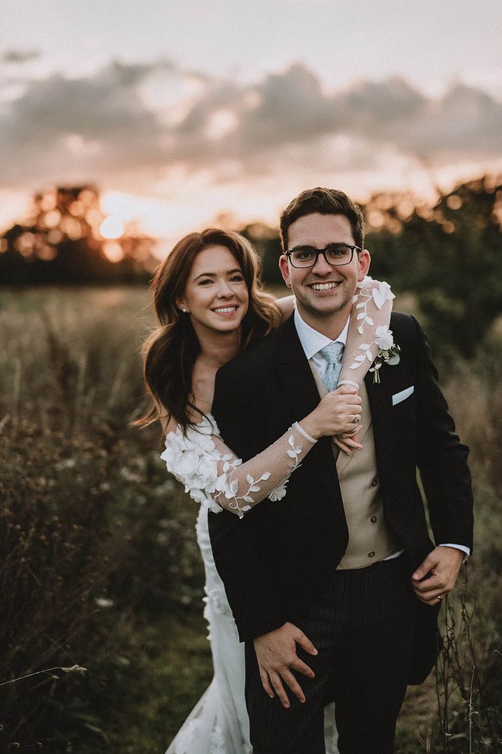 The bride in a floral off the shoulder wedding dress embraces the groom at their 60k wedding 