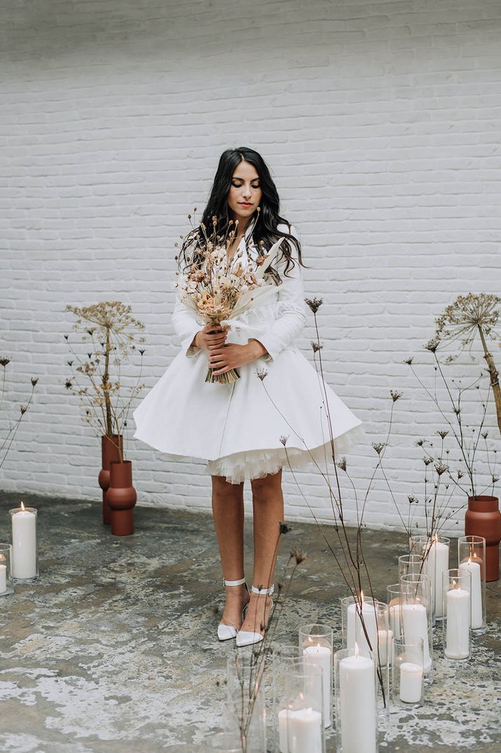 Bride wearing short blazer wedding dress with long sleeves and tulle layered skirt 