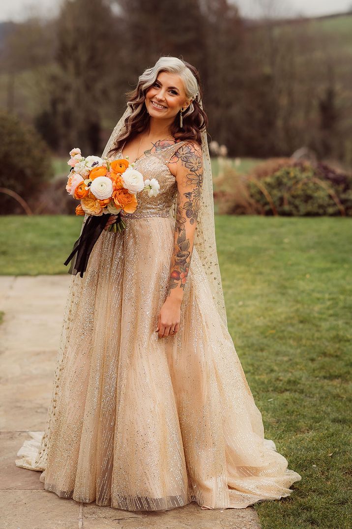 Bride in untraditional sparkling gold wedding dress with orange autumnal wedding bouquet 