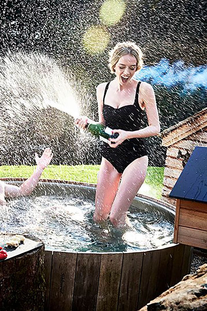 Image of a woman spraying a bottle of bubbles in a hot tub