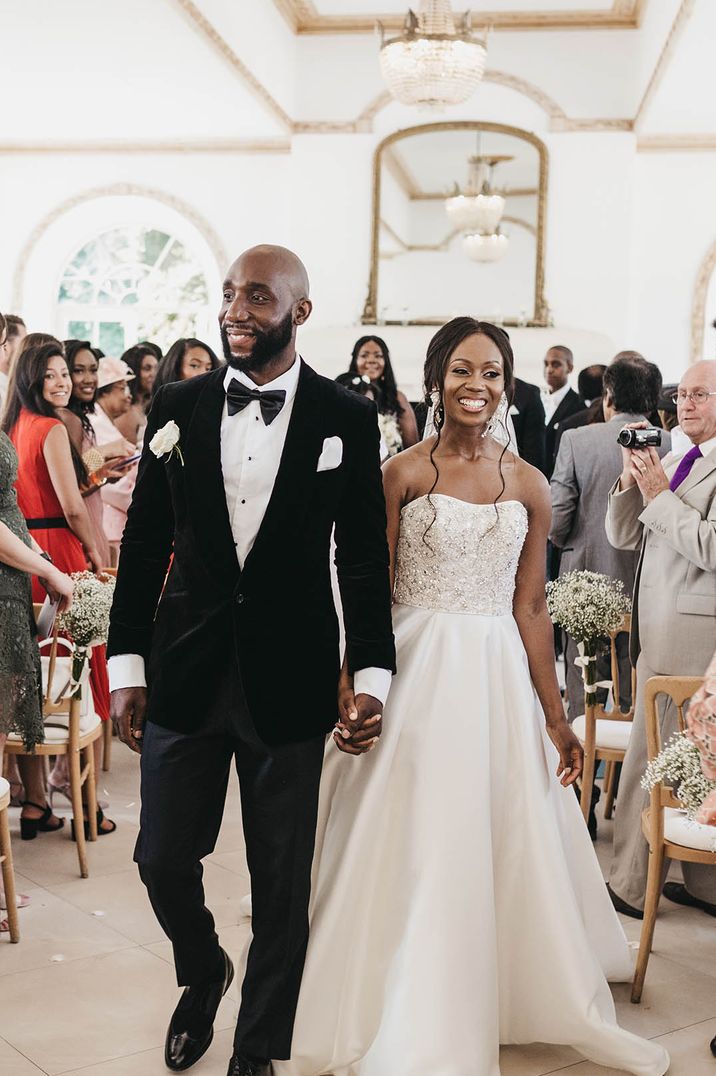 Bride in strapless wedding dress and cathedral length veil and her new husband in black suit