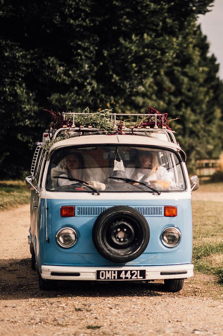 Baby blue and white camper van with florals and fauna on top - wedding transport