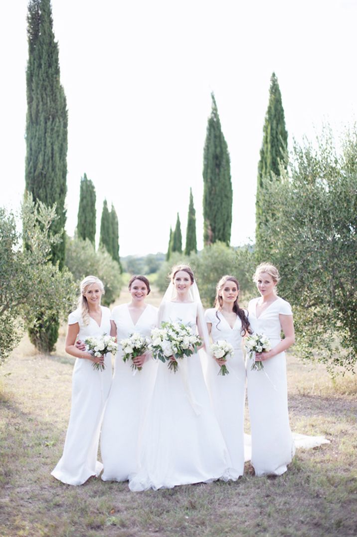 Bridesmaids wearing v neck long white bridesmaid dresses