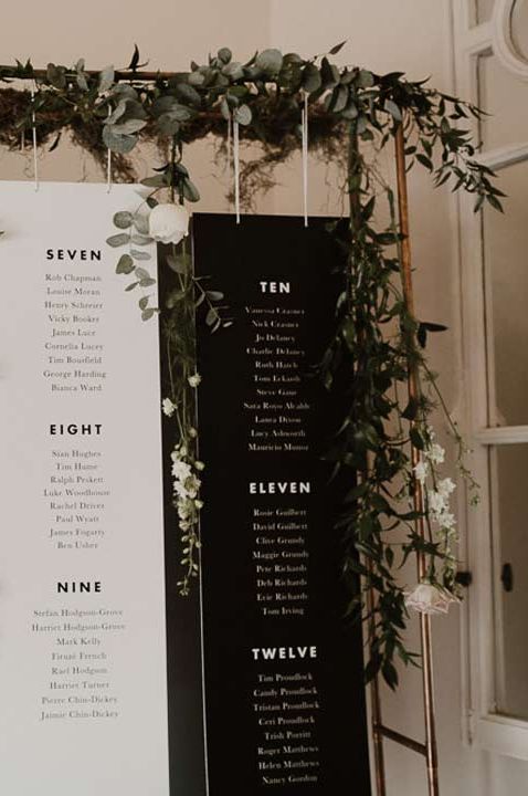 Four hanging monochrome table plan signs with greenery and fauna hanging around them