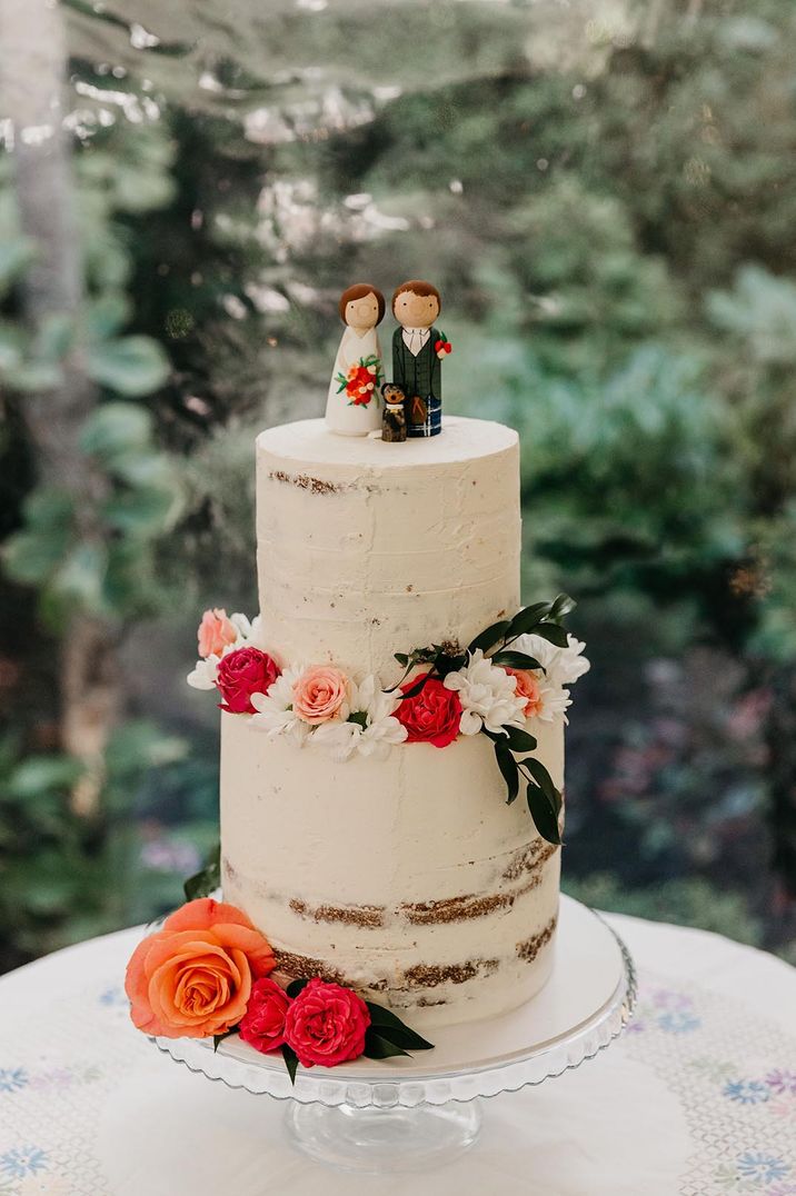 Two tiered buttercream wedding cake with rose and foliage decorations and personalised wedding cake toppers 