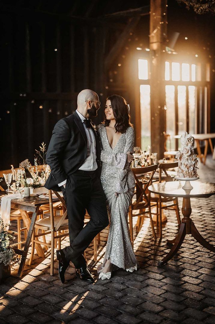 Silver sparkly wedding dress and tuxedo at rustic barn Elmley Nature Reserve wedding venue in Kent 